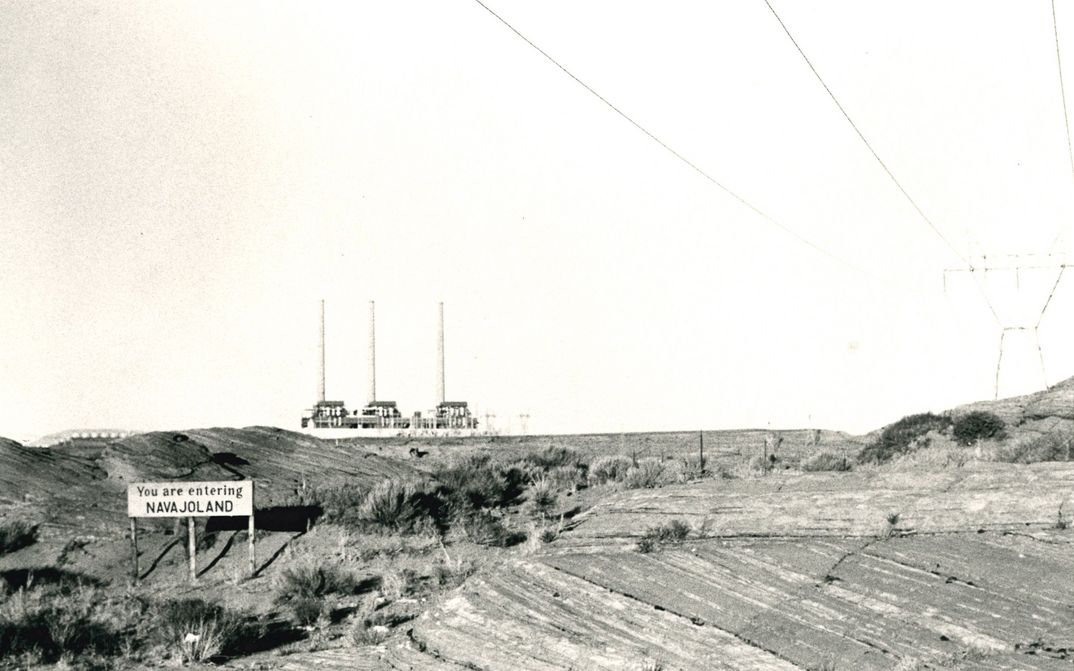 Film still from SACRIFICE AREA: View of a barren landscape, a sign says: " You are entering Navajoland".