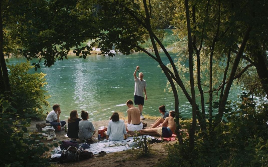 Film still from BURNING FIRE: A group of young people celebrating on the banks of a river.