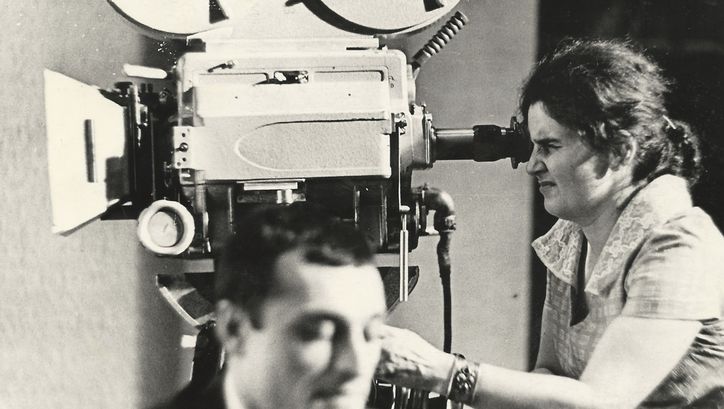 Filmstill aus "Deda-Shvili an rame ar aris arasodes bolomde bneli" von Lana Gogoberidze. Zu sehen ist ein Schwarz-Weiß-Bild einer Frau, die eine Videokamera benutzt. 