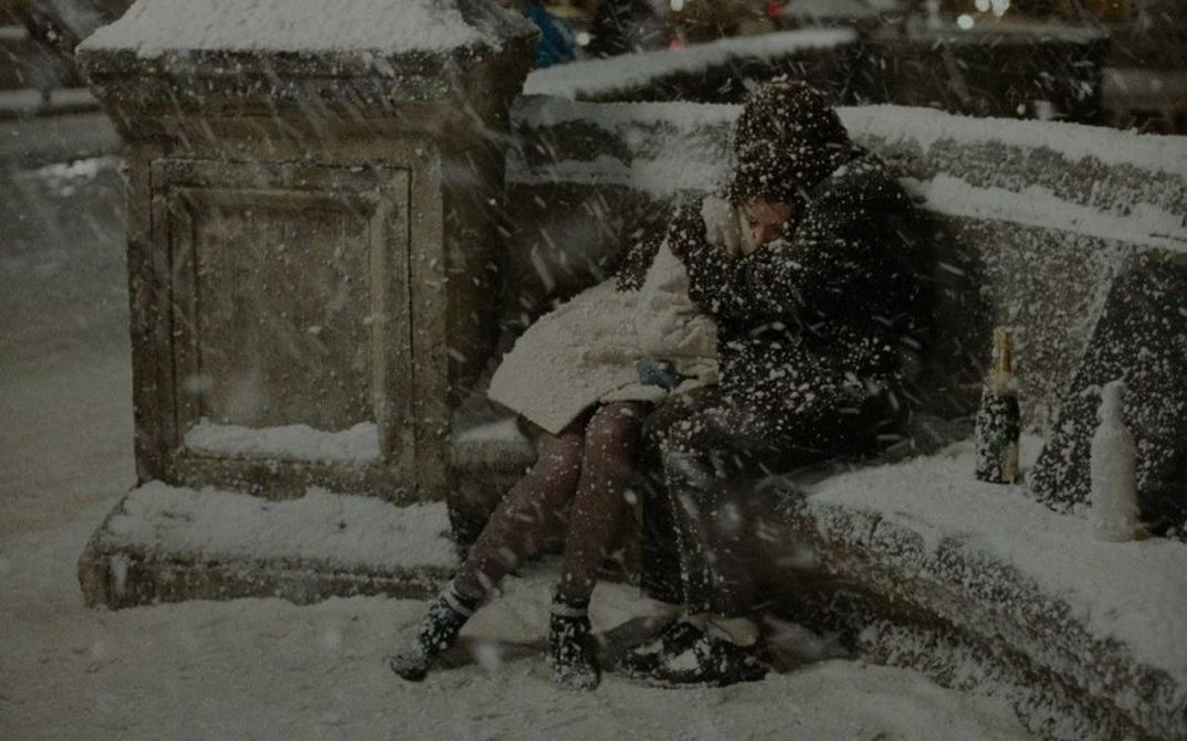 Filmstill aus LES AMANTS DU PONT-NEUF: Ein Liebespaar umarmt sich im dichten Schneetreiben auf einer Bank.