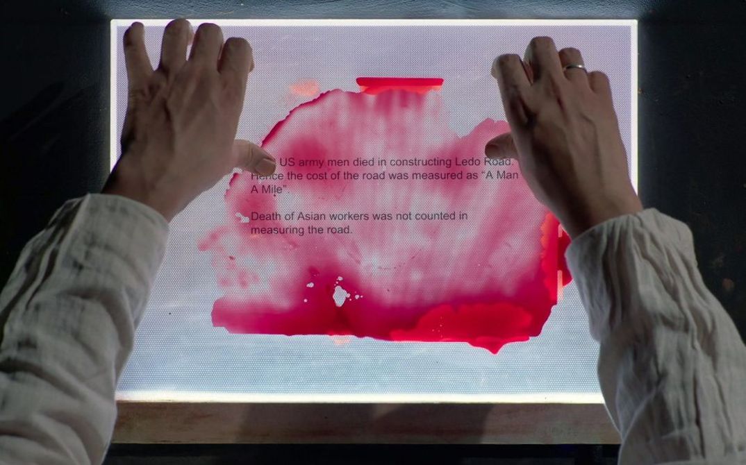 Hände halten Papier mit Text und roter Flüssigkeit auf Leuchttisch.