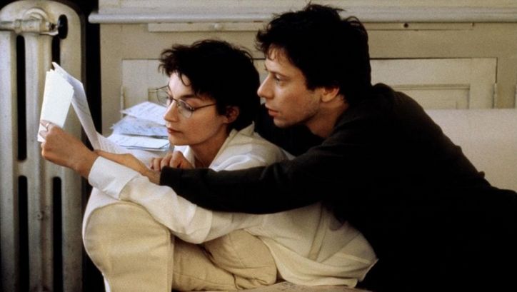 Filmstill aus COMMENT JE ME SUIS DISPUTÉ .. (MA VIE SEXUELLE). Ein Mann und eine Frau liegen auf einem Sofa und lesen gemeinsam in einem Manuskript. 