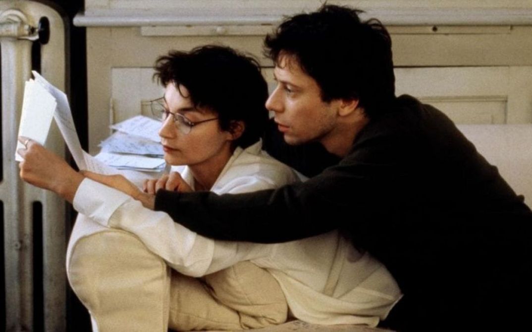 Filmstill aus COMMENT JE ME SUIS DISPUTÉ .. (MA VIE SEXUELLE). Ein Mann und eine Frau liegen auf einem Sofa und lesen gemeinsam in einem Manuskript.