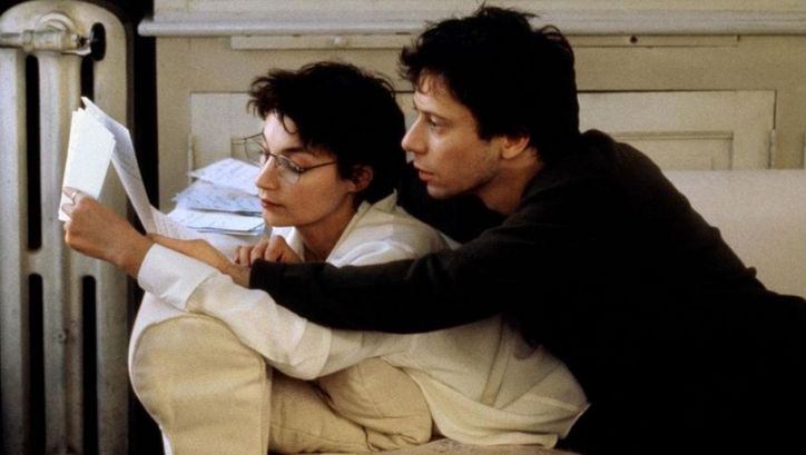 Filmstill aus COMMENT JE ME SUIS DISPUTÉ .. (MA VIE SEXUELLE). Ein Mann und eine Frau liegen auf einem Sofa und lesen gemeinsam in einem Manuskript. 