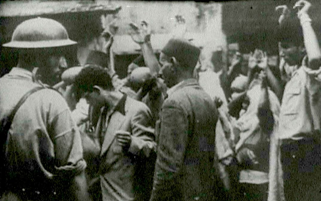 Film still from the unfinished film "Insurrectionelle": A street scene, several people hold up their hands.