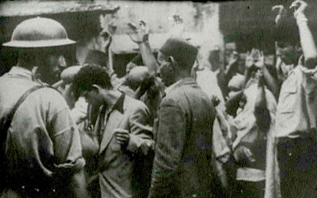 Filmstill aus dem unvollendeten Film "Insurrectionelle": Eine Straßenszene, mehrere Menschen halten ihre Hände hoch.