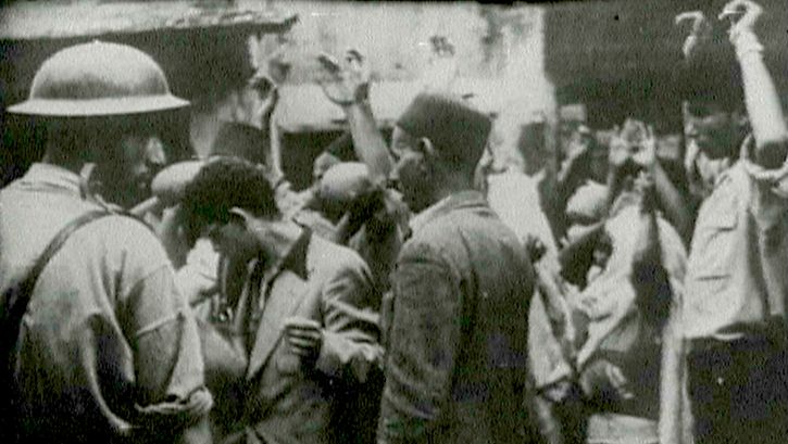 Film still from the unfinished film "Insurrectionelle": A street scene, several people hold up their hands.