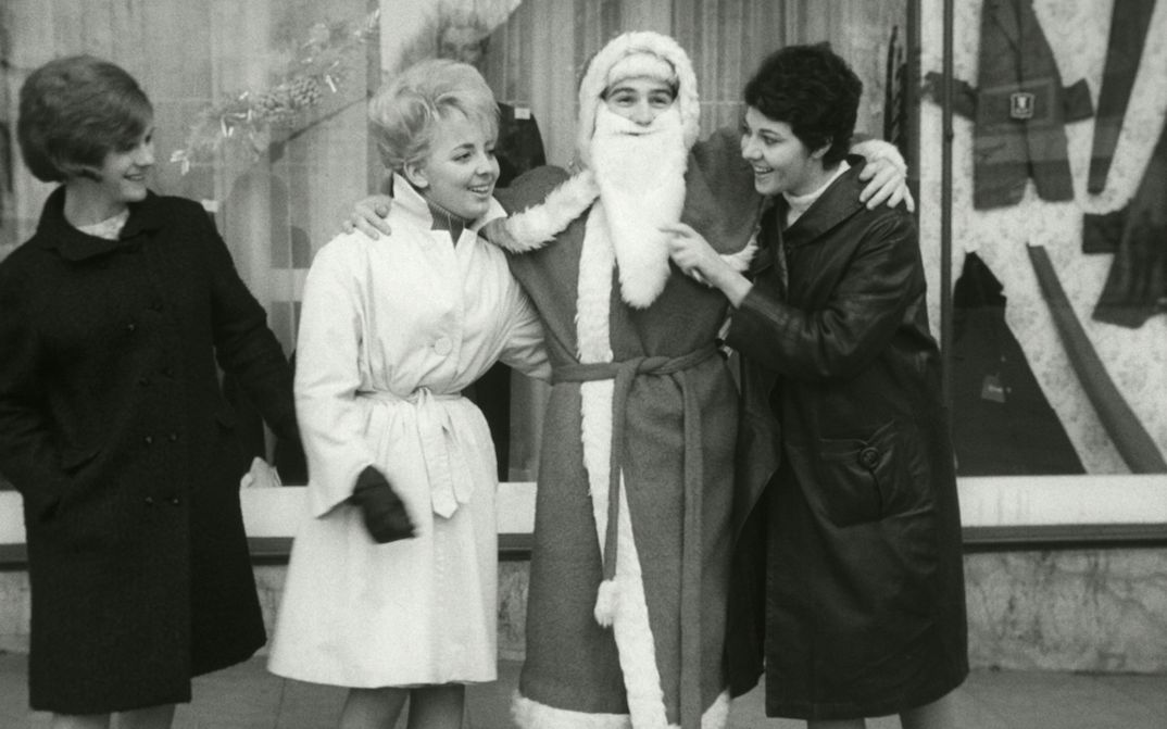 Filmstill aus LE PÈRE NOEL A LES YEUX BLEUS: Drei Frauen stehen vor einem Schaufenster neben einem Weihnachtsmann und scherzen mit ihm.