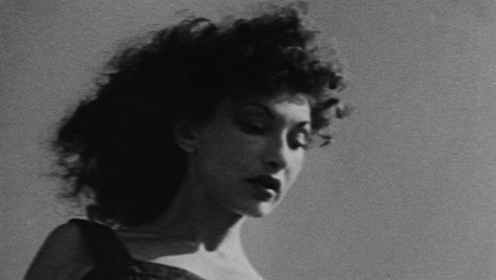 Film still from AT LAND: Black and white photo of a woman with dark curls, taken slightly below her head.
