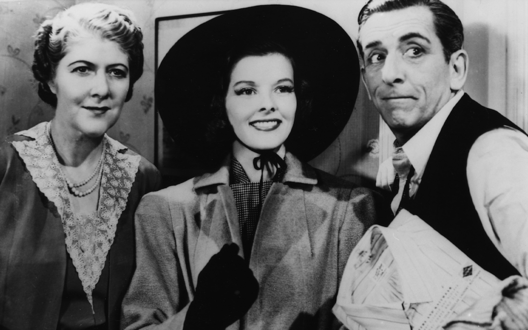 Filmstill aus HOLIDAY: Edward Everett Horton steht neben zwei Frauen, alle blicken in die gleiche Richtung, er schneidet eine Grimasse.