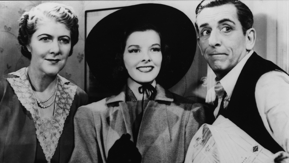Filmstill aus HOLIDAY: Edward Everett Horton steht neben zwei Frauen, alle blicken in die gleiche Richtung, er schneidet eine Grimasse.