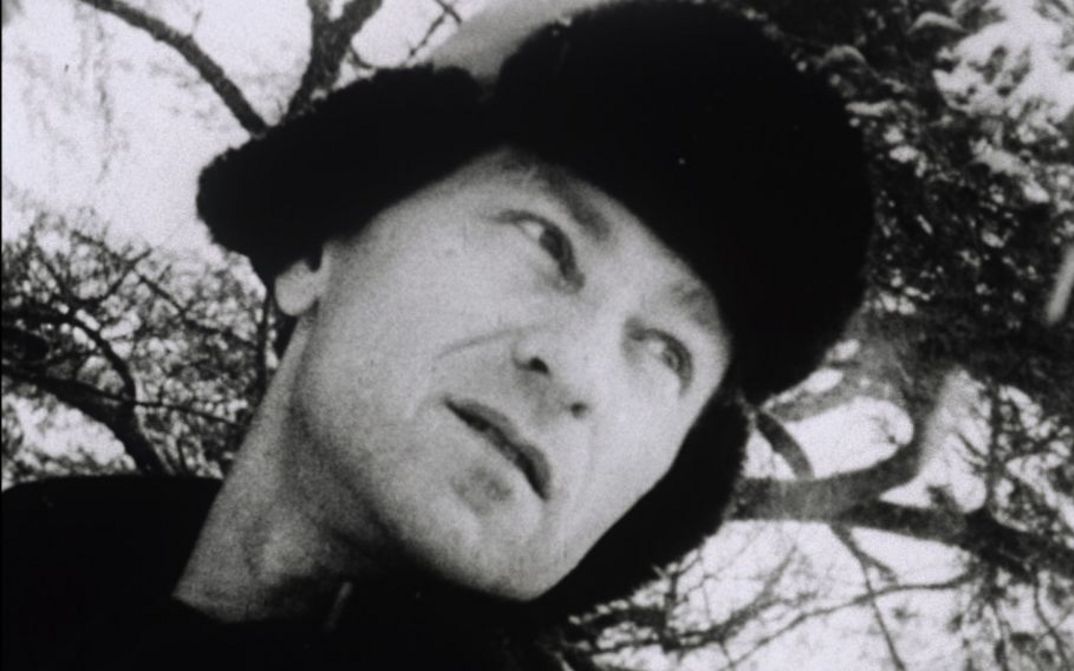 Filmstill aus LOST LOST LOST. Man sieht Jonas Mekas mit Pelzmütze, der nachdenklich in die Ferne schaut.