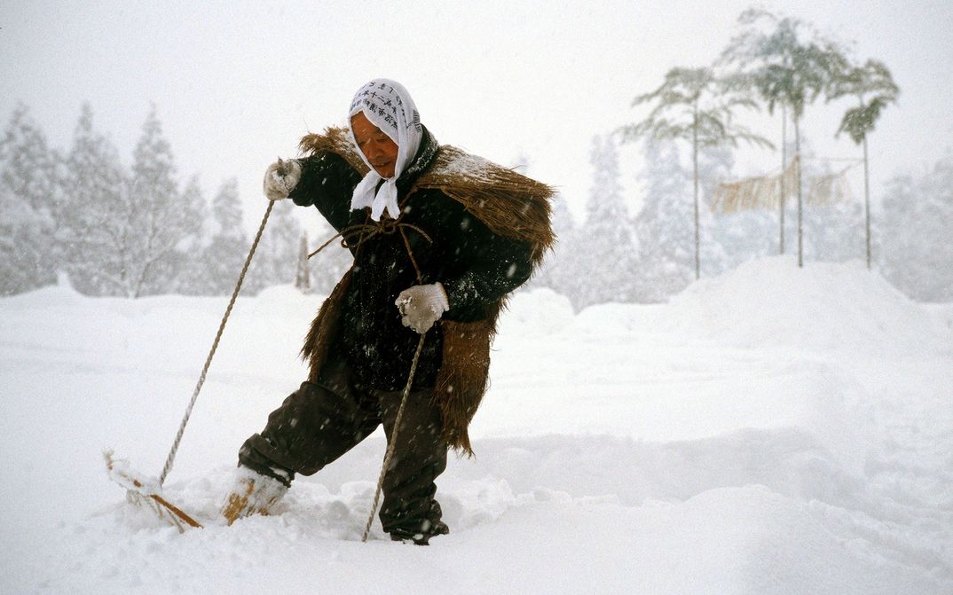 Filmstill aus UNTER SCHNEE: Eine Person in einem historischen Kostüm läuft mit Schneeschuhen durch eine verschneite Landschaft.