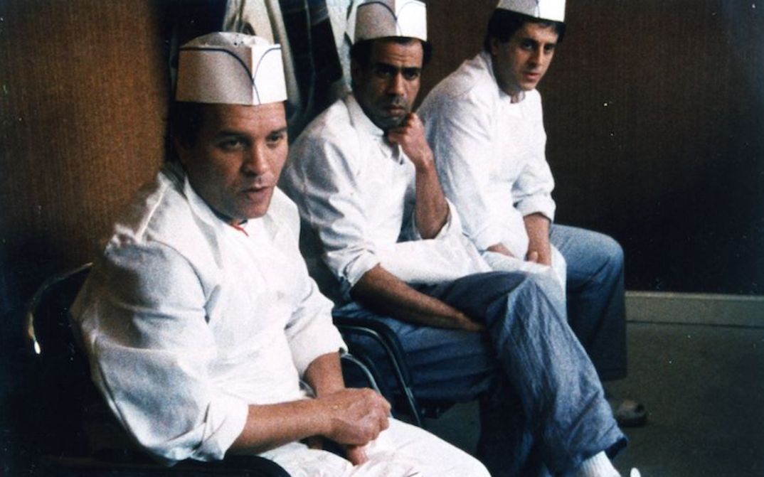 Filmstill aus COÛTE QUE COÛTE: Drei Männer in weißer Kochkleidung sitzen nebeneinander.