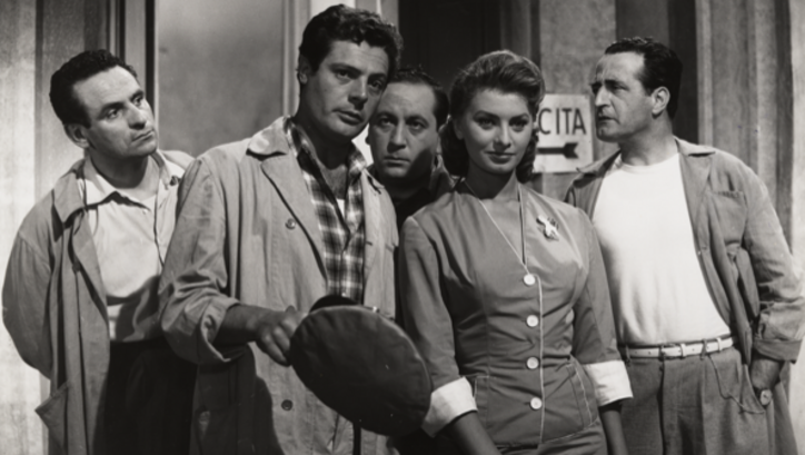 Film still from PECCATO CHE SIA UNA CANAGLIA: Marcello Mastroianni in work clothes and Sophia Loren are standing next to each other, behind them three men, all of whom are looking at Mastroianni.