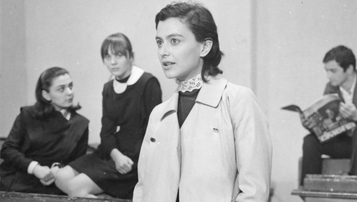 Film still from WHEN ALMONDS BLOSSOMED: You can see some young people standing and sitting between school desks.