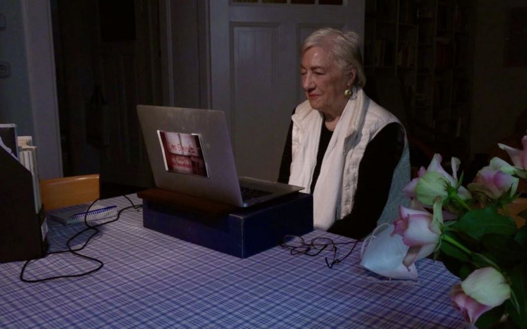 Filmstill aus HELKE SANDER: AUFRÄUMEN: Helke Sander sitzt mit einem aufgeschlagenen Laptop am Küchentisch.