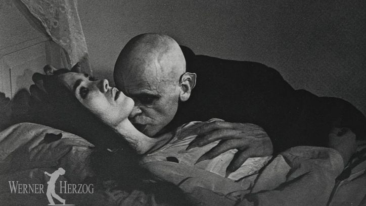 Filmstill aus NOSFERATU – PHANTOM DER NACHT: Klaus Kinski als Vampir ist dabei, eine im Bett liegende junge Frau in den Hals zu beißen.