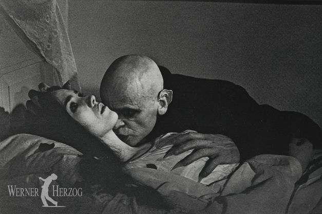 Filmstill aus NOSFERATU – PHANTOM DER NACHT: Klaus Kinski als Vampir ist dabei, eine im Bett liegende junge Frau in den Hals zu beißen.