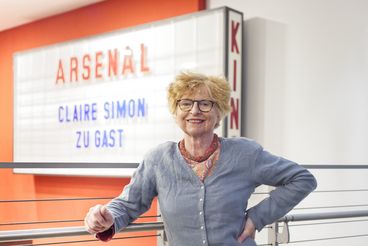 Porträt von Claire Simon vor der Leuchtanzeige mit ihrem Namen