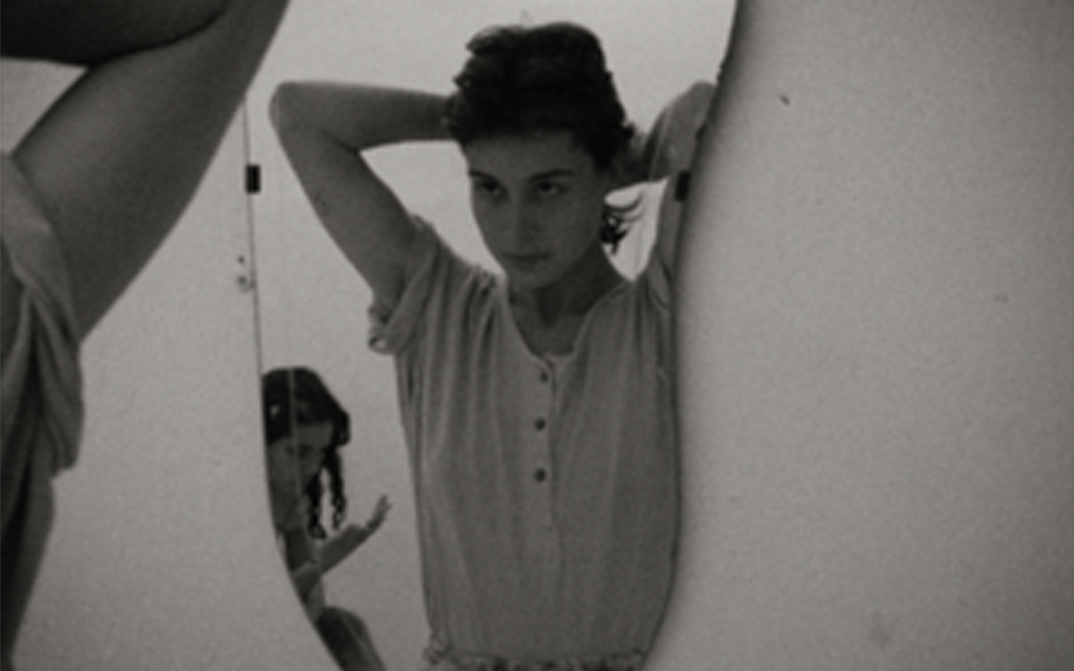 Filmstill from ANZIEHEN. A young woman is looking into a mirror.