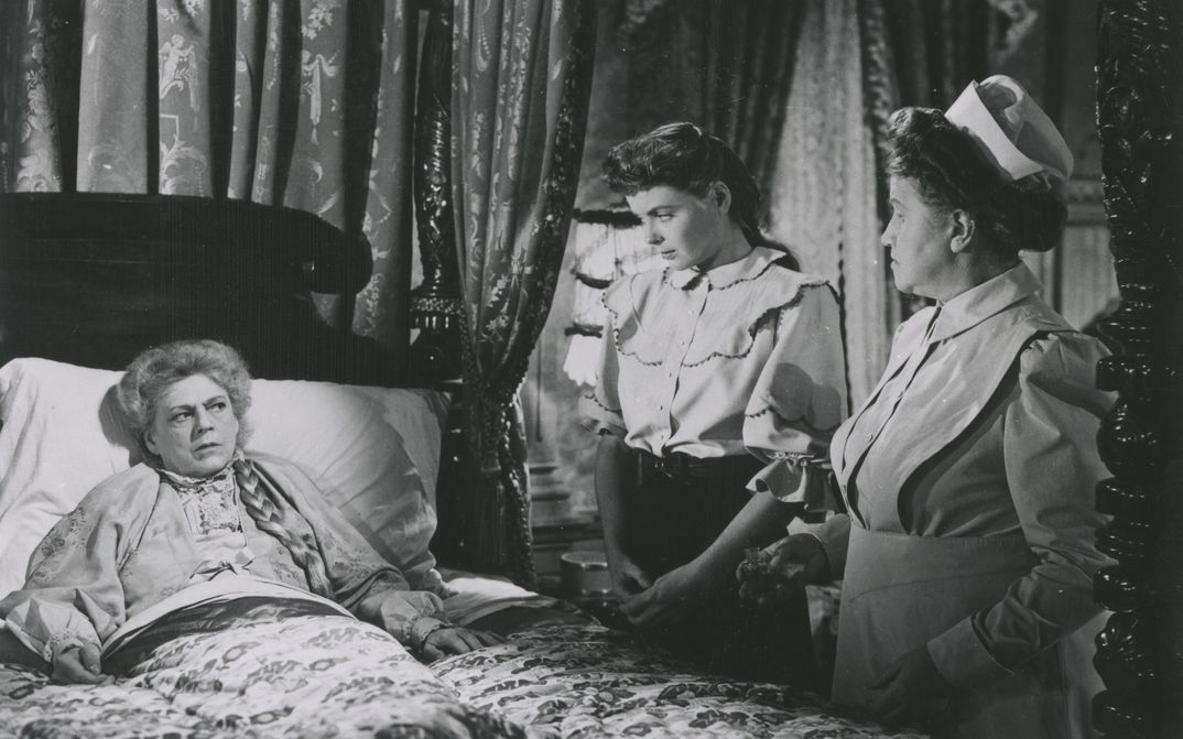 Film still from THE SPIRAL STAIRCASE: An elderly woman is lying in bed, a nurse and a young woman are standing next to the bed.