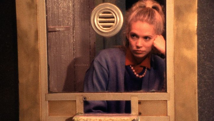 Film still from VARIETY: A young woman sits in a ticket booth with a bored expression on her face.