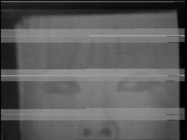 Still from “Blinking” by Takahiko Iimura: a black and white video image, with glitches, showing a blurred face.