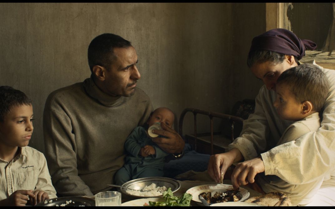 Filmstill aus FEATHERS. Eine Familie mit drei kleinen Kindern sitzt am Esstisch.