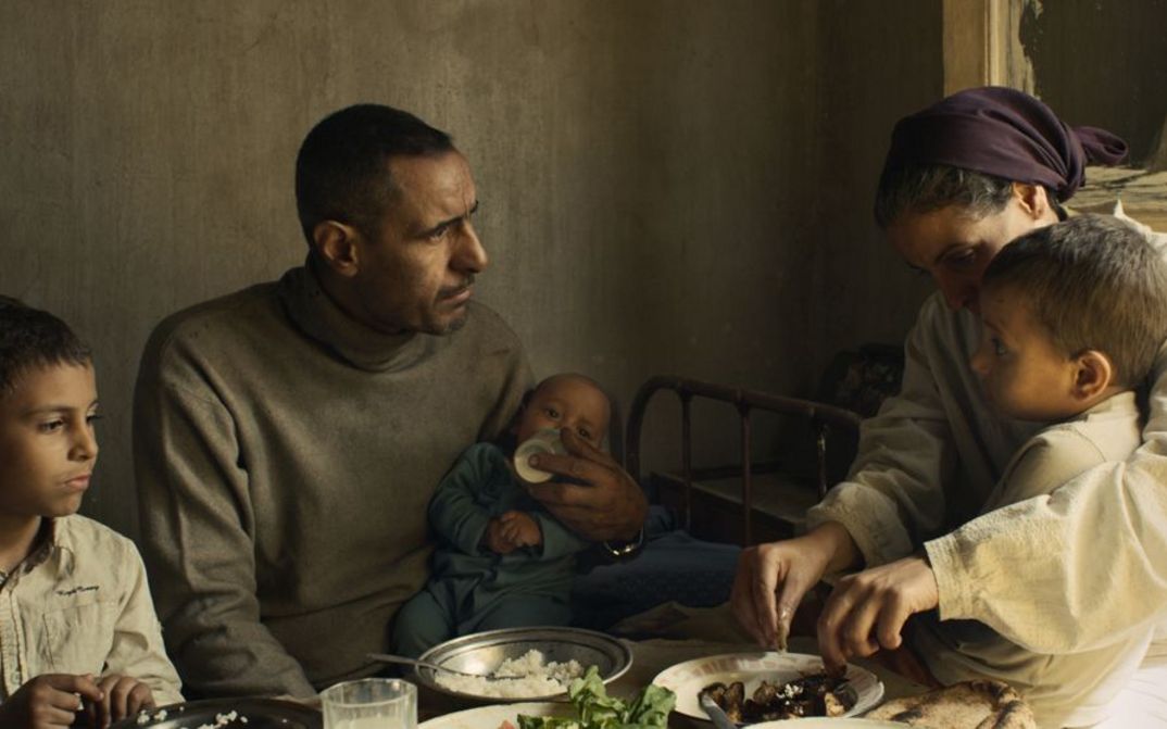 Film still from FEATHERS. A family with three small children is sitting at the dining table.