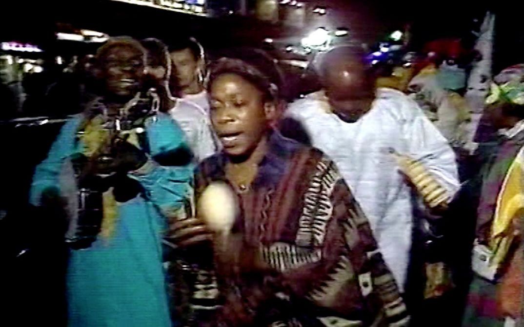 Filmstill aus dem Film "Moune Ô" von Maxime Jean-Baptiste. Menschen laufen mit Musikinstrumenten in den Händen durch eine volle straße
