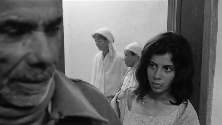 Film still from OS FUZIS: People in a small room.