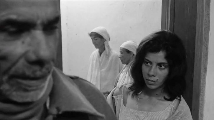 Film still from OS FUZIS: People in a small room.