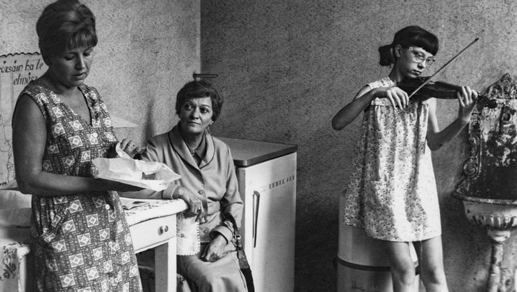 Filmstill aus The Lady from Constantinople: In einer Küche sitzen zwei Frauen und ein Mädchen spielt Geige.