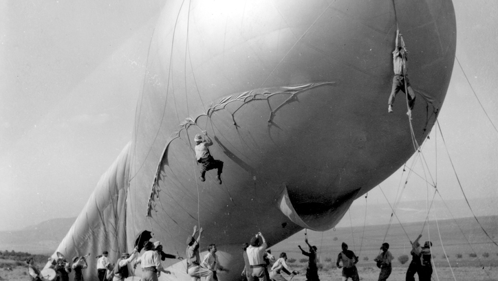 Filmstill aus THE ATTACHED BALLOON. Männer halten die Seile eines großen Sperrballons, zwei von ihnen schweben in der Luft.