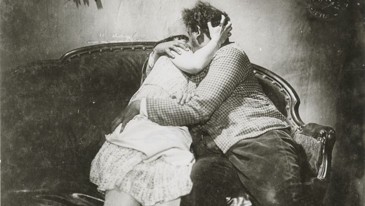 Filmstill aus SO IST DAS LEBEN: Eine Frau und ein Mann küssen und umarmen sich auf einem Sofa.
