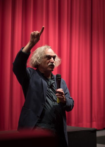 Eugene Green vor Kinovorhang mit Mikrofon