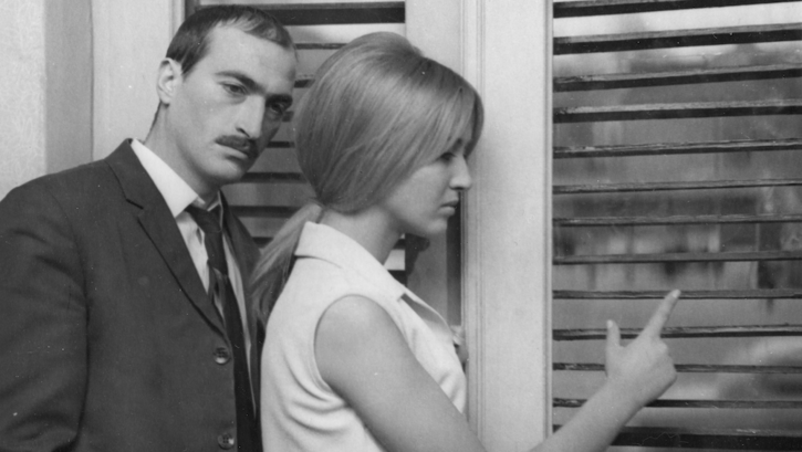 Film still from LIMITS: A man and a woman are standing at a window, both looking thoughtful.