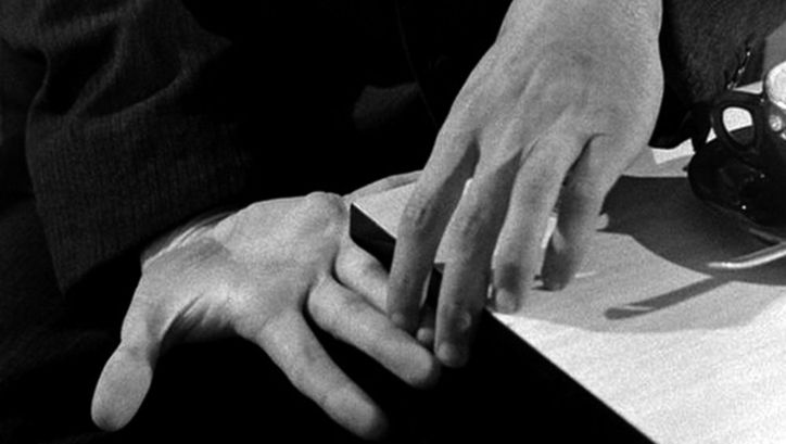 Filmstill aus PICKPOCKET: Zwei Hände, die sich mit den Fingerspitzen berühren.