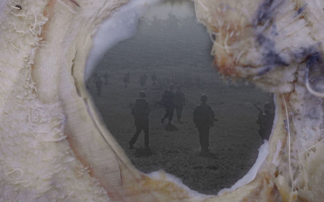 Film still from NOWHERE NEAR: An old photograph of soldiers can be seen through an opening.
