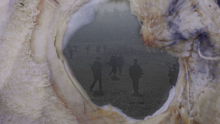 Film still from NOWHERE NEAR: An old photograph of soldiers can be seen through an opening.