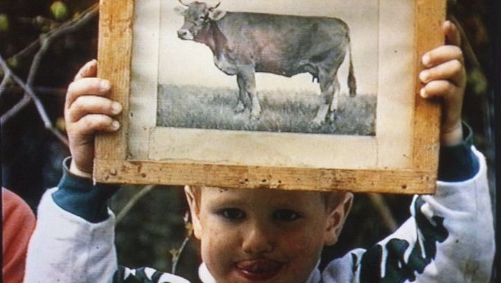 Film still from DER GRÜNE BERG: A child holds up a picture of a cow.