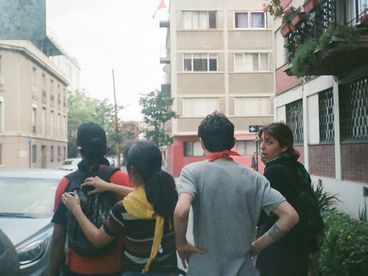 35mm colour photo of four young people seen from behind, on a sidewalk. The one on the right is turning back to look at the others.