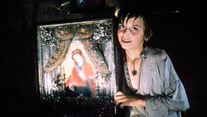  Film still from THE WHITE BIRD MARKED WITH BLACK: A boy holds up an icon.