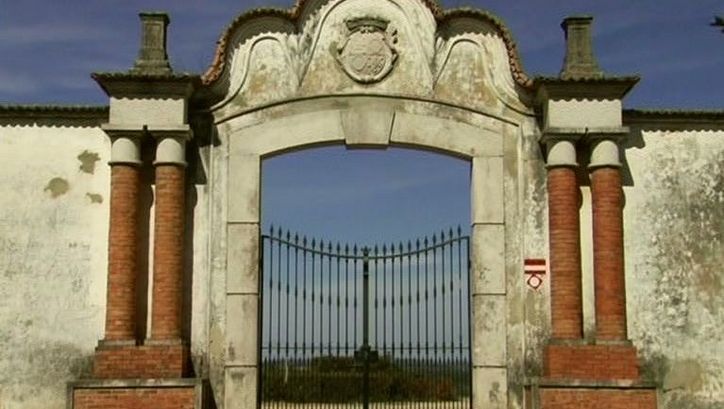 Film still from LINHA VERMELHA: View of an iron gate surrounded by walls.