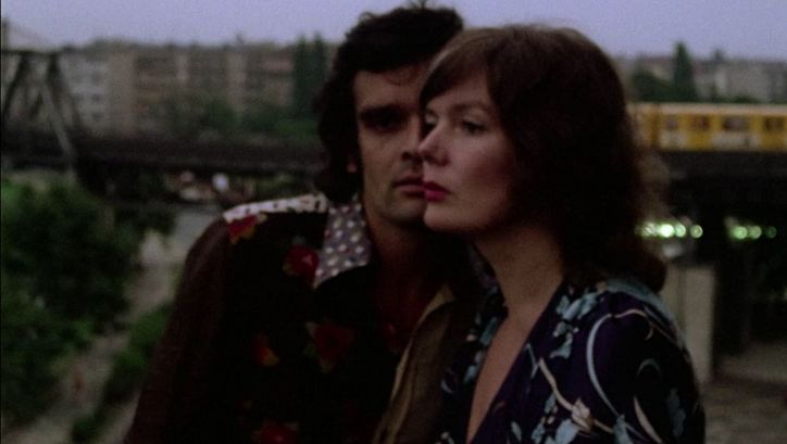 Film still from ERZÄHLEN. The faces of a man and a woman half uperimposed. In the background the elevated railroad.