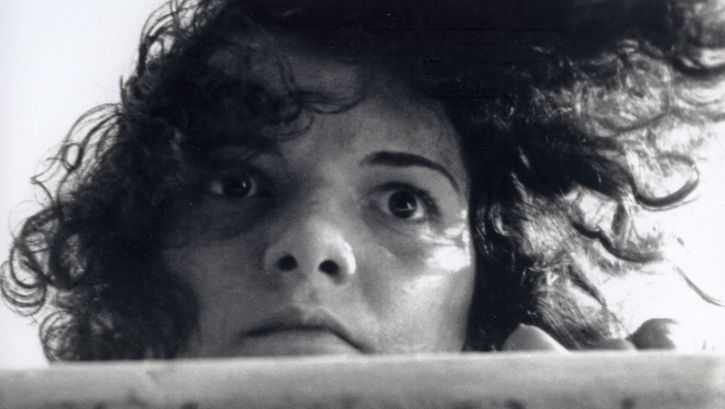 Film still from LIMITE: A young woman with disheveled hair gazes fixedly into the distance.