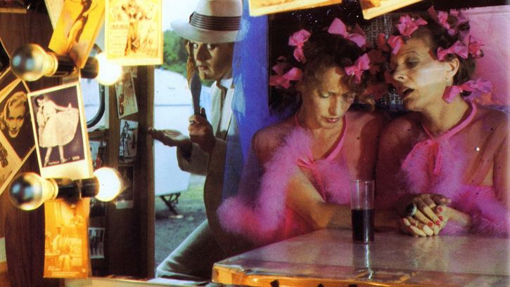 Film still from FREAK ORLANDO: Three people at a counter decorated with lots of photos.
