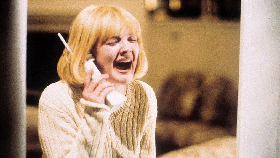 Film still from SCREAM: A young blonde woman holds a telephone receiver to her ear. Her face is contorted by a scream.