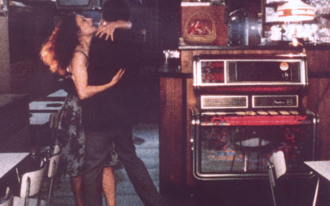 Filmstill aus TOUTE UNE NUIT: In einem ansonsten leeren Lokal tanzen eng umschlungen eine Frau und ein Mann. Neben ihnen steht eine Jukebox.